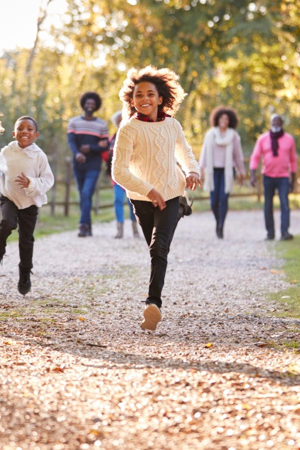 Children Running Ahead As Multi Generation Family Enjoy Autumn Walk In Countryside Together