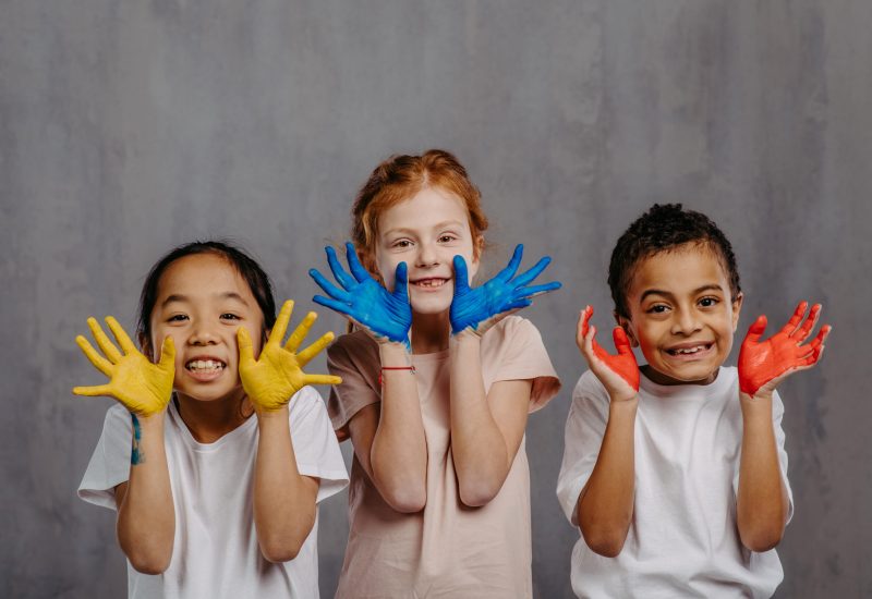 Portrait of happy kids with painted hands, studio shoot.