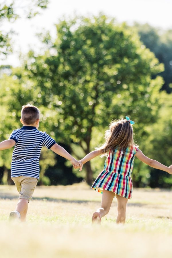 Three little children running on a green field